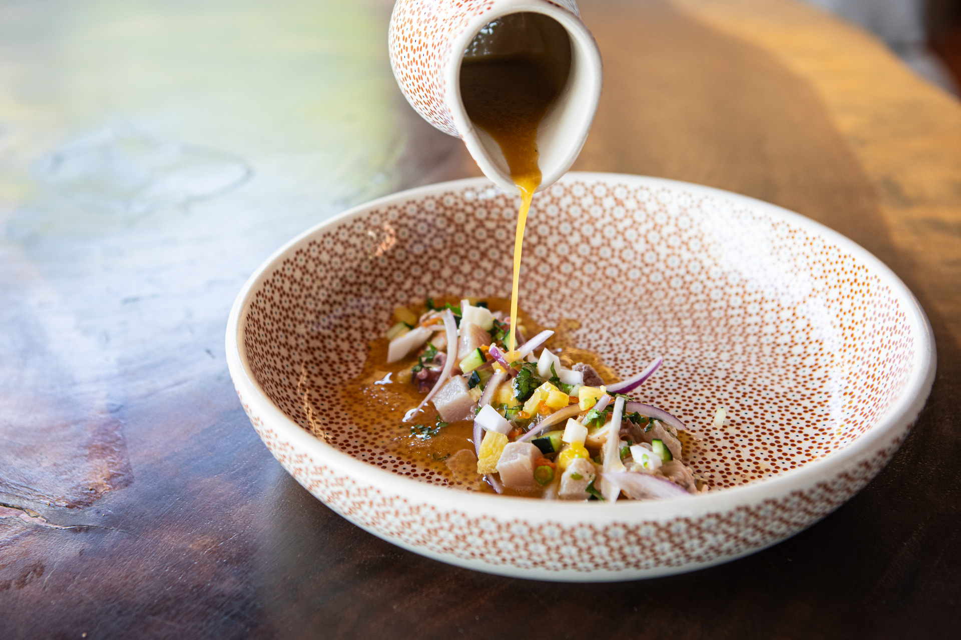 A chef is preparing a plate of food on a table.