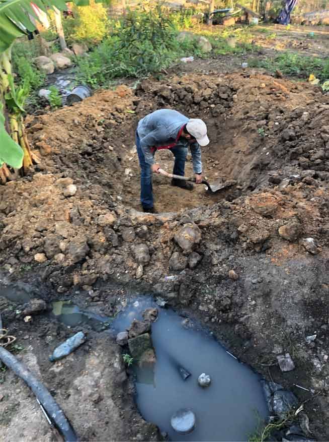 A man is digging a hole in the dirt with a shovel.