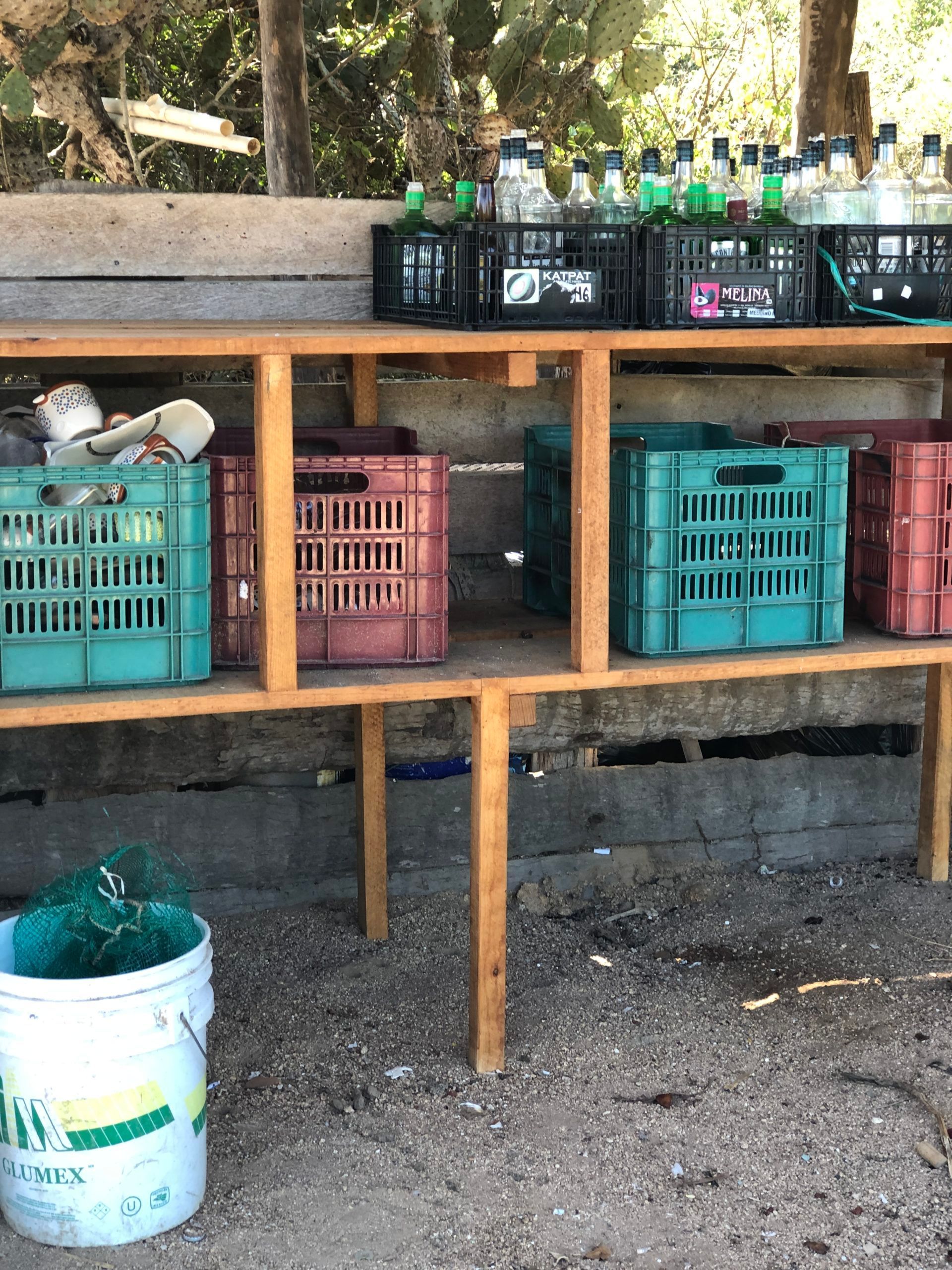 A wooden shelf with crates and bottles on it.