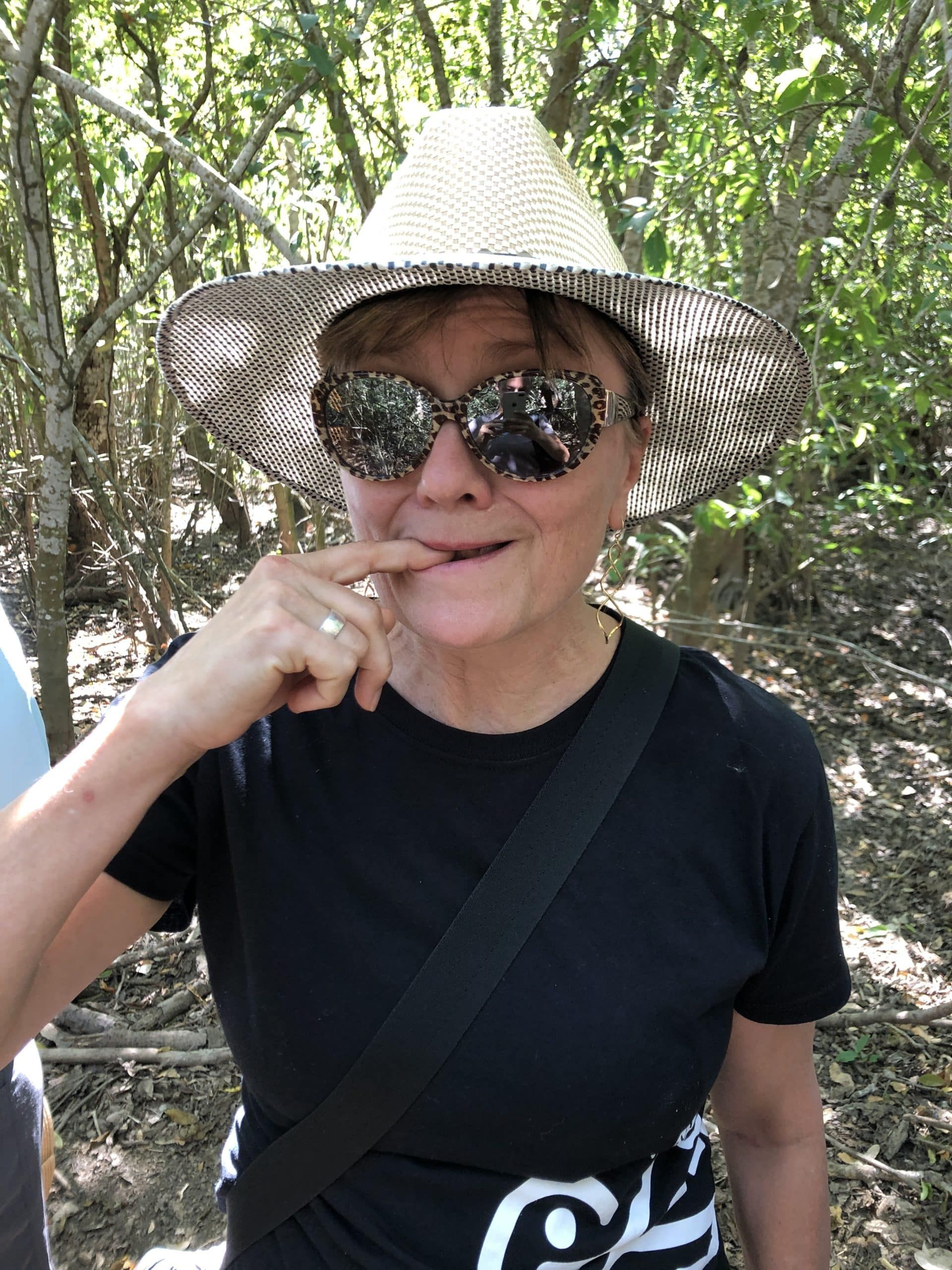 A woman wearing a hat and sunglasses covering her mouth