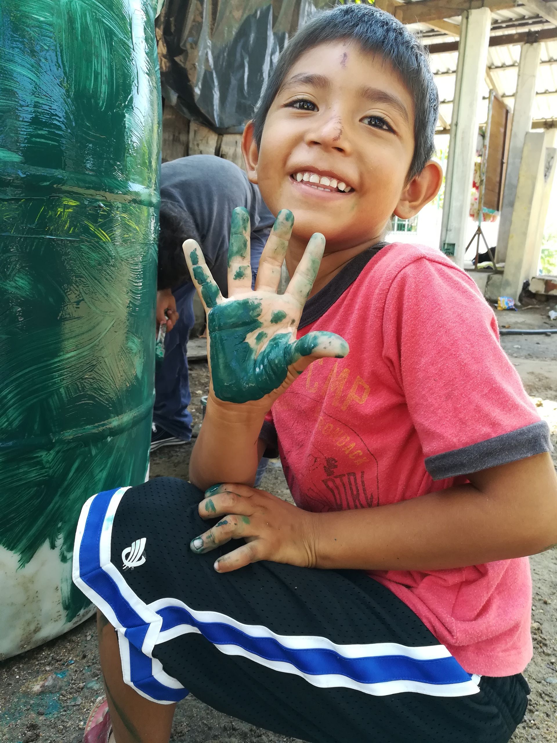 A young boy with his hands covered in green paint