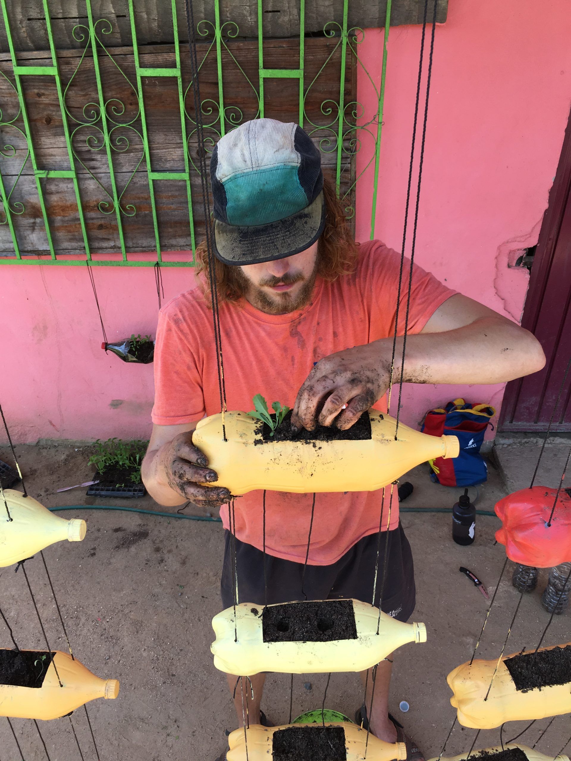 A man is planting a plant in a yellow bottle