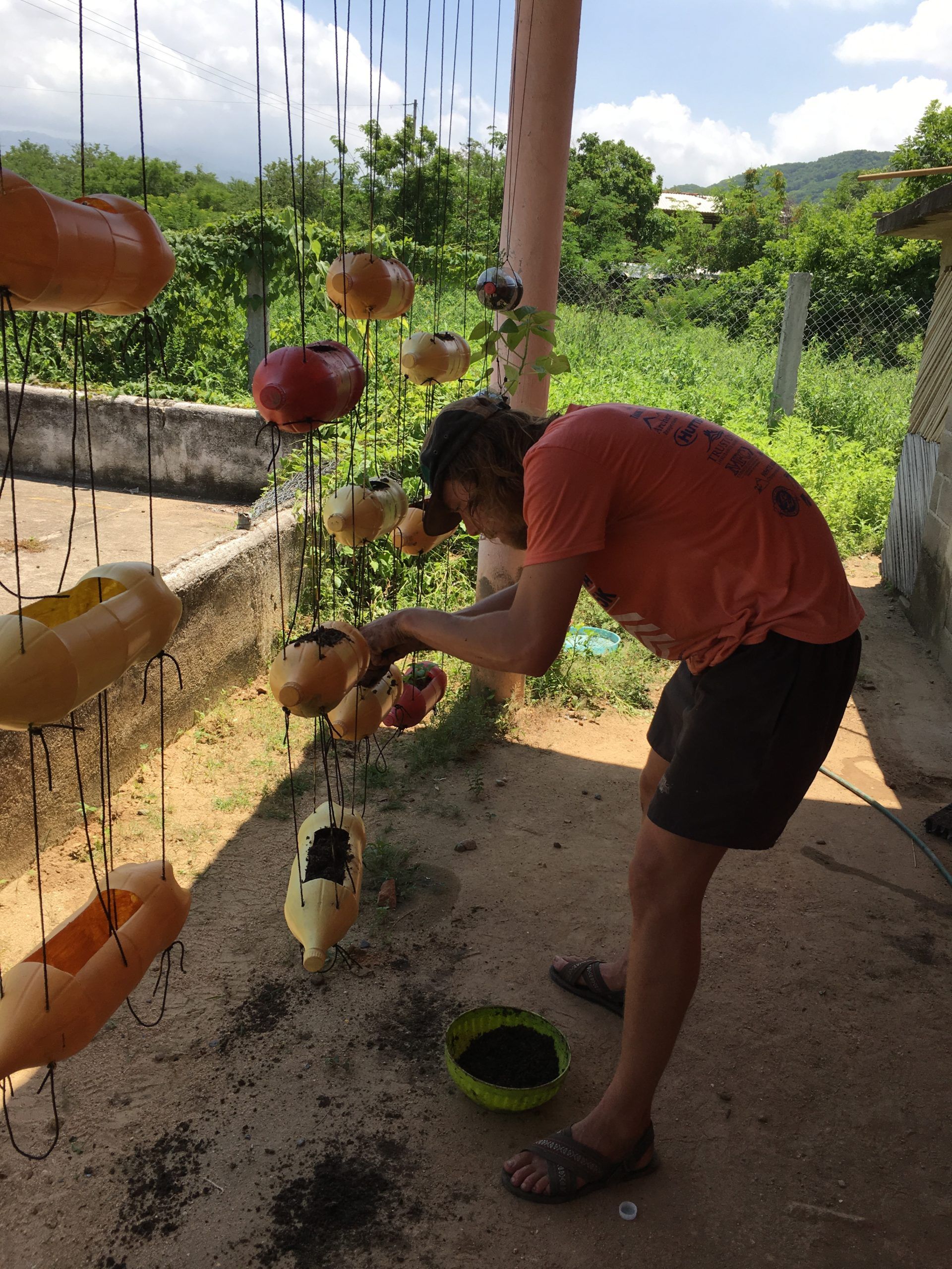 A man in an orange shirt is standing on a porch