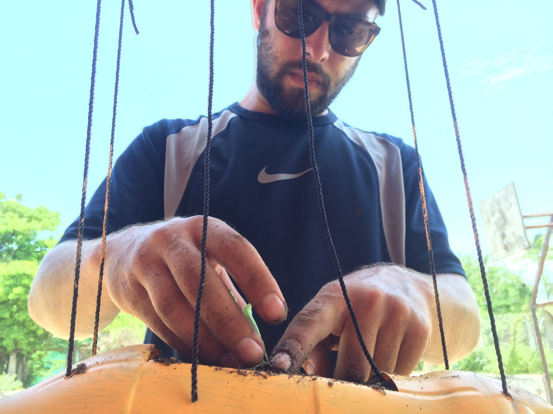 A man wearing sunglasses and a nike shirt is working on a puppet.