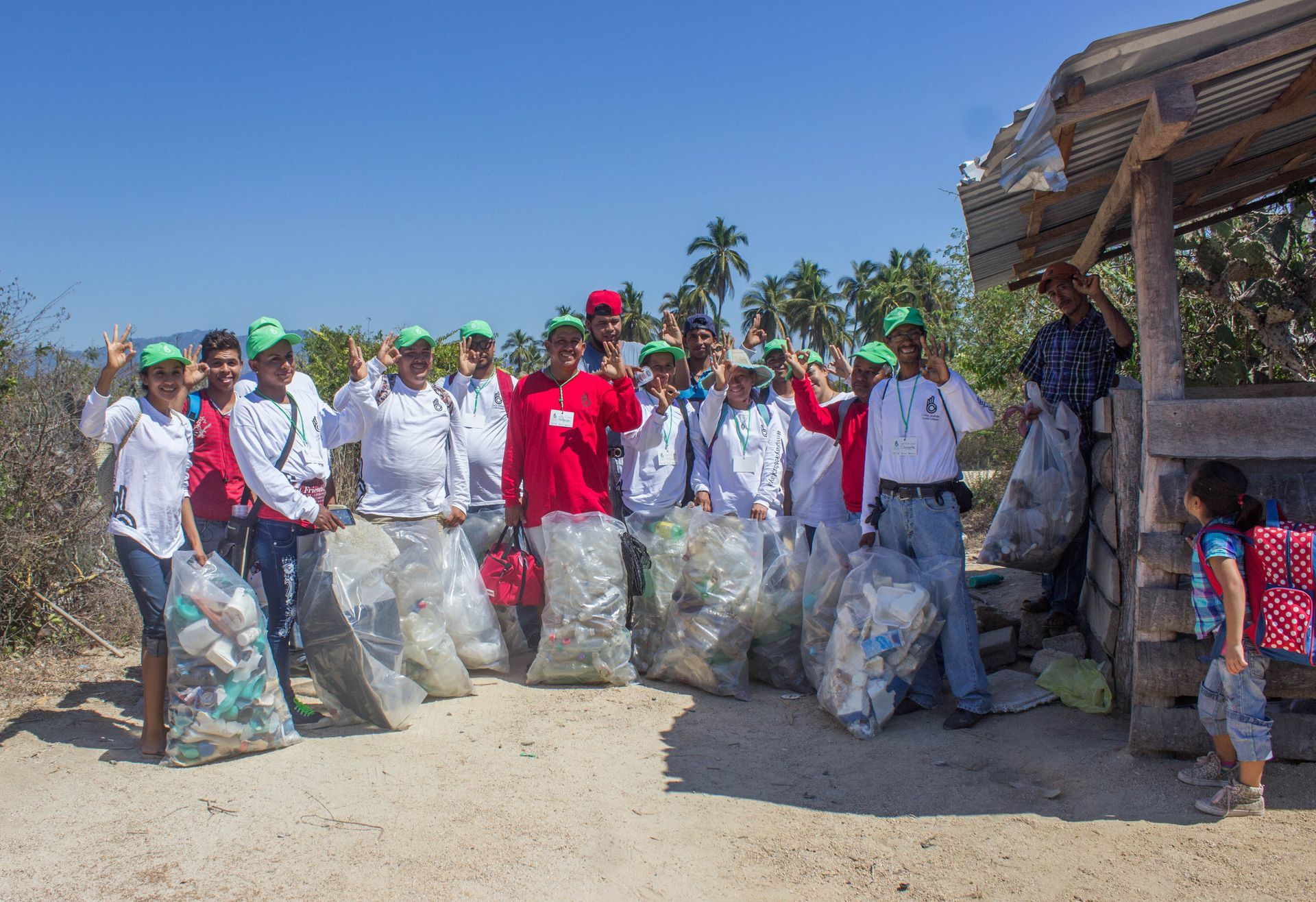 A group of people standing next to each other holding bags of trash.