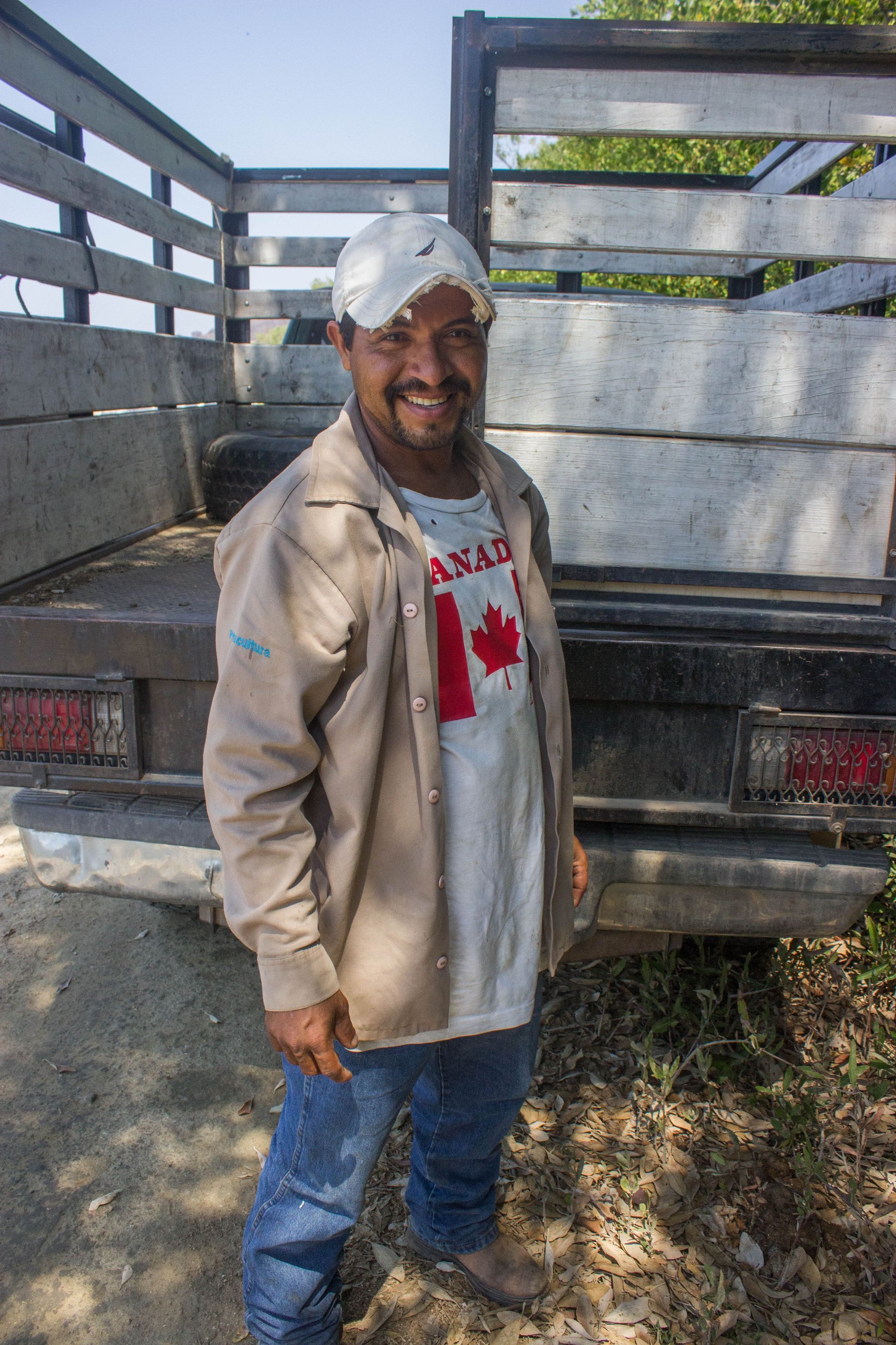 A man wearing a canadian flag shirt is standing in front of a truck.