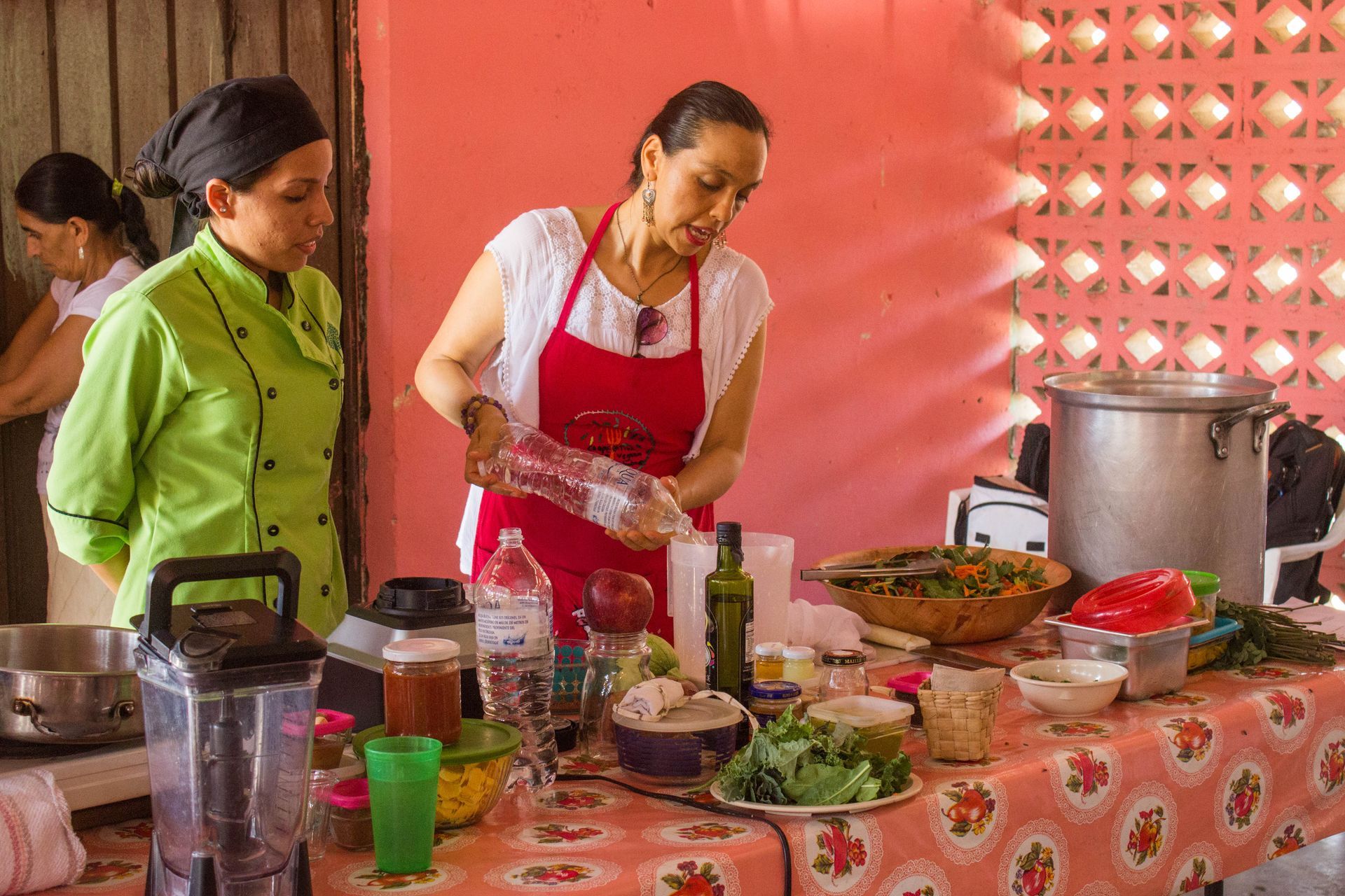 Two women are standing at a table preparing food.