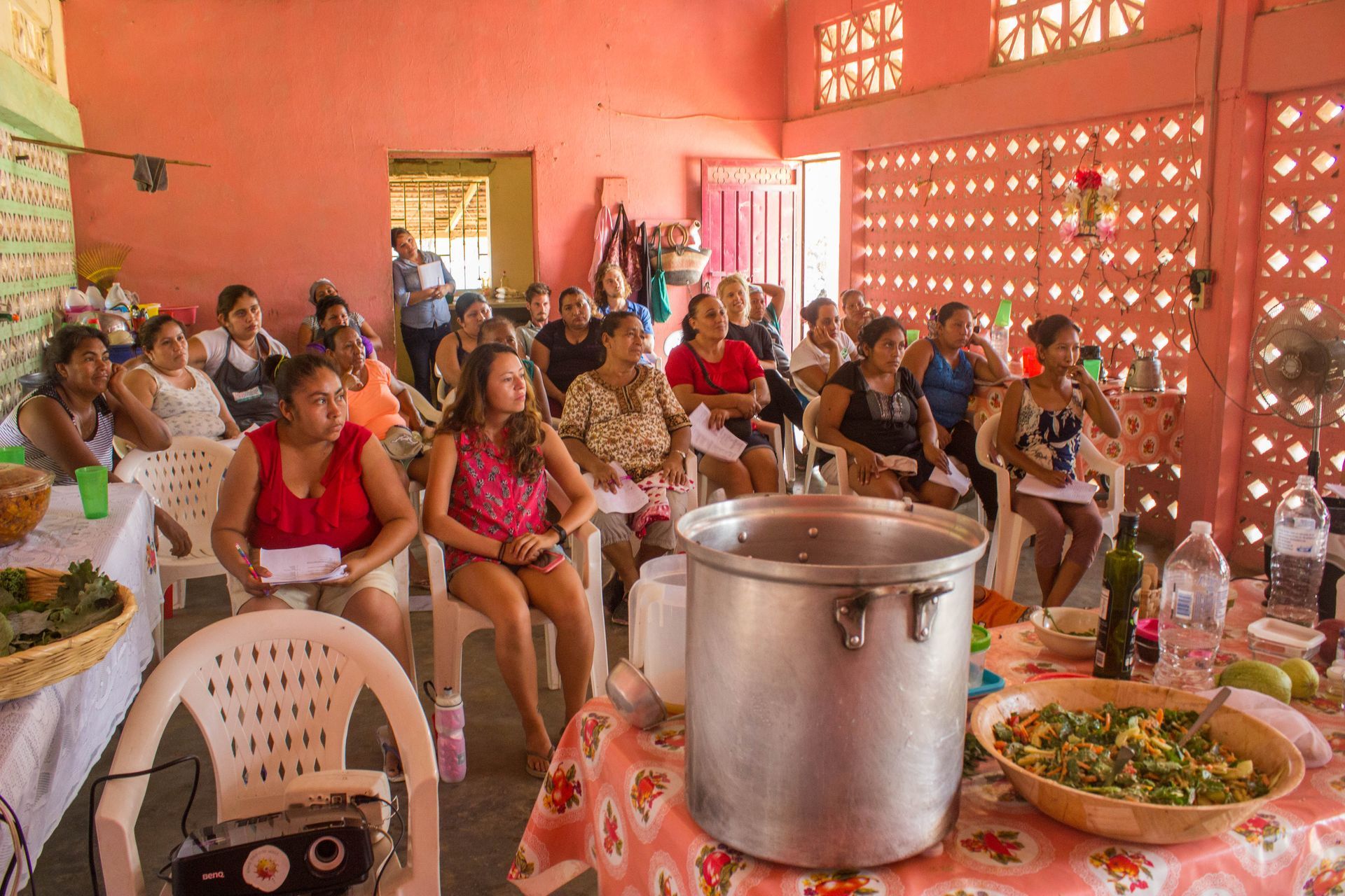 A group of people are sitting around a table with a pot of food.