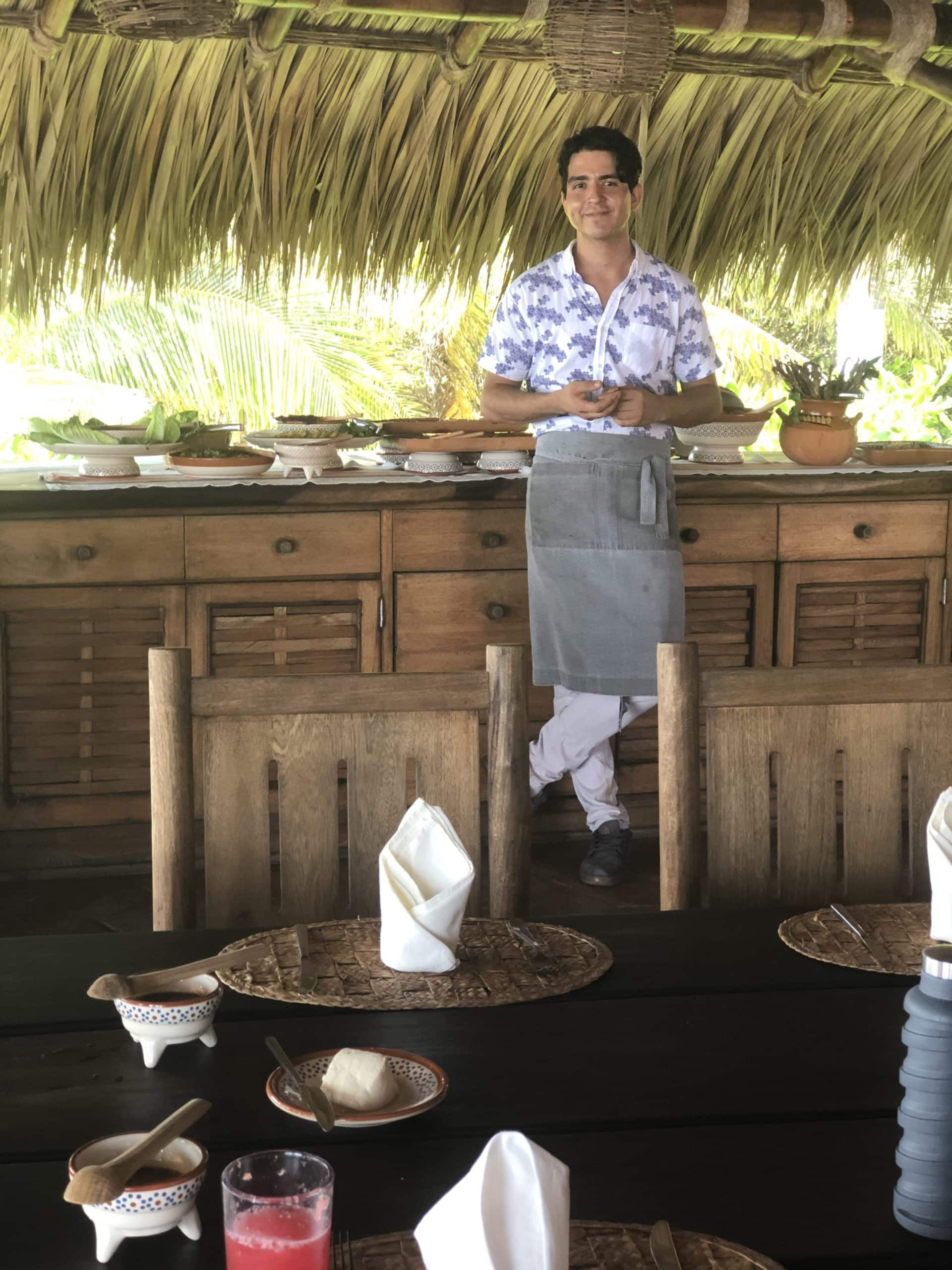 A man is standing in front of a table with plates and napkins on it.