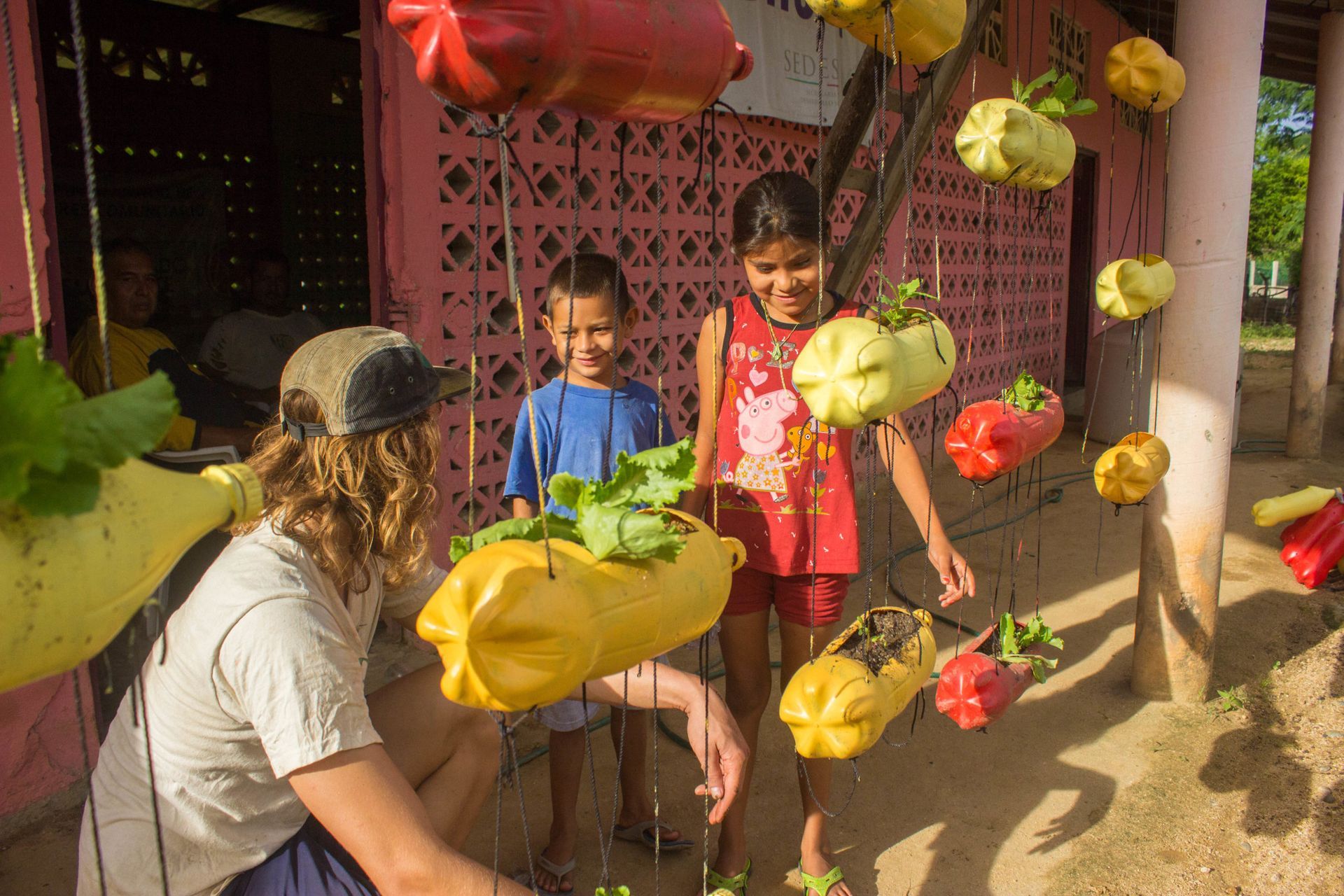 A man and two children are standing in front of a pink building.