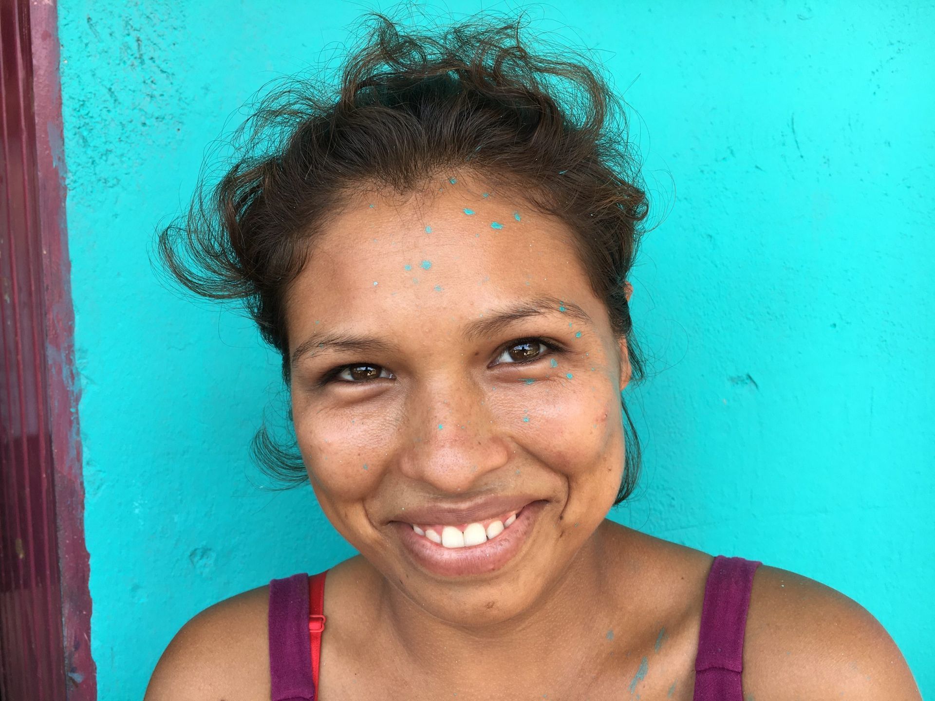 A woman is smiling in front of a blue wall.