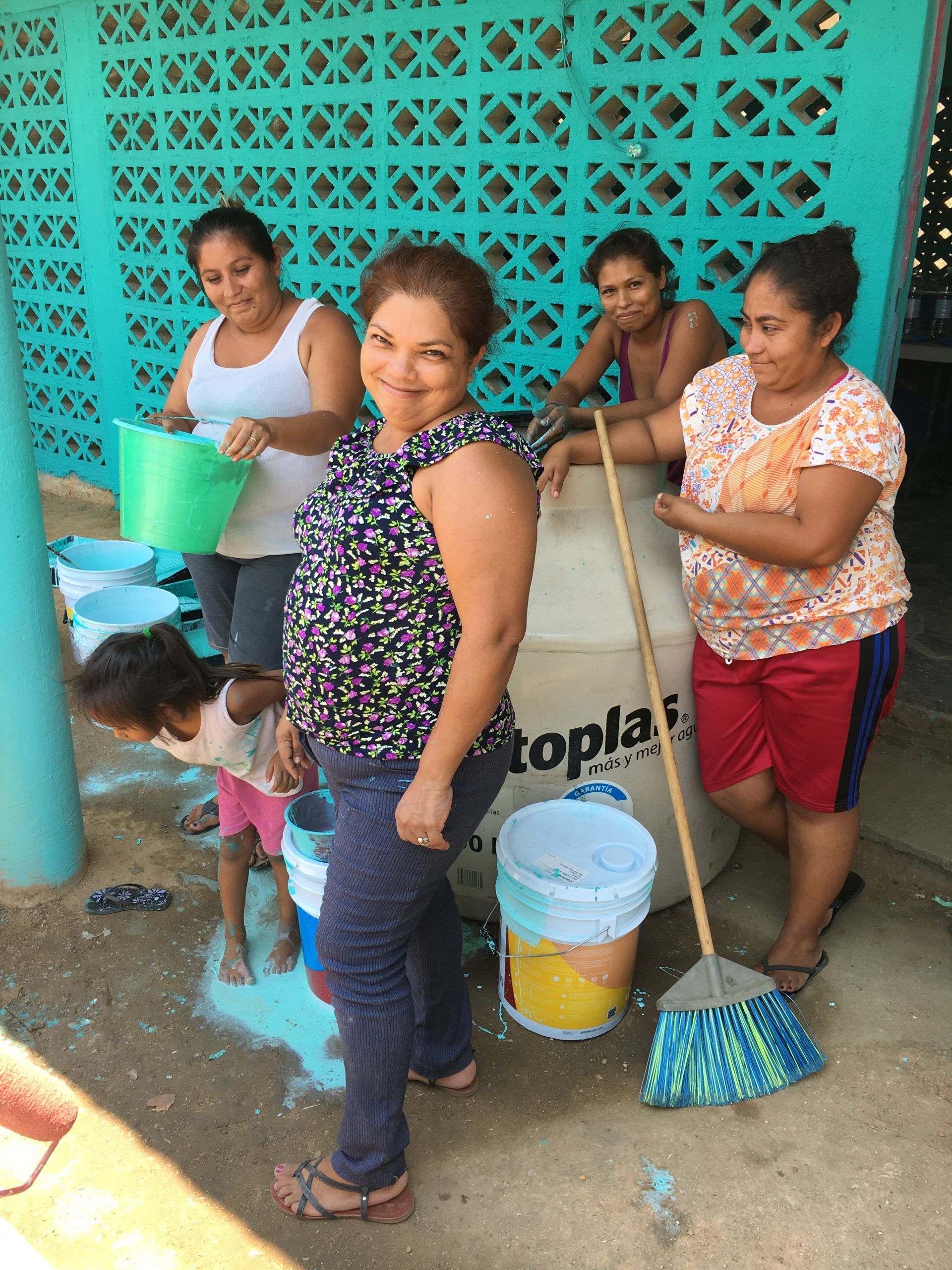 A group of women are standing around a tank that says toplas