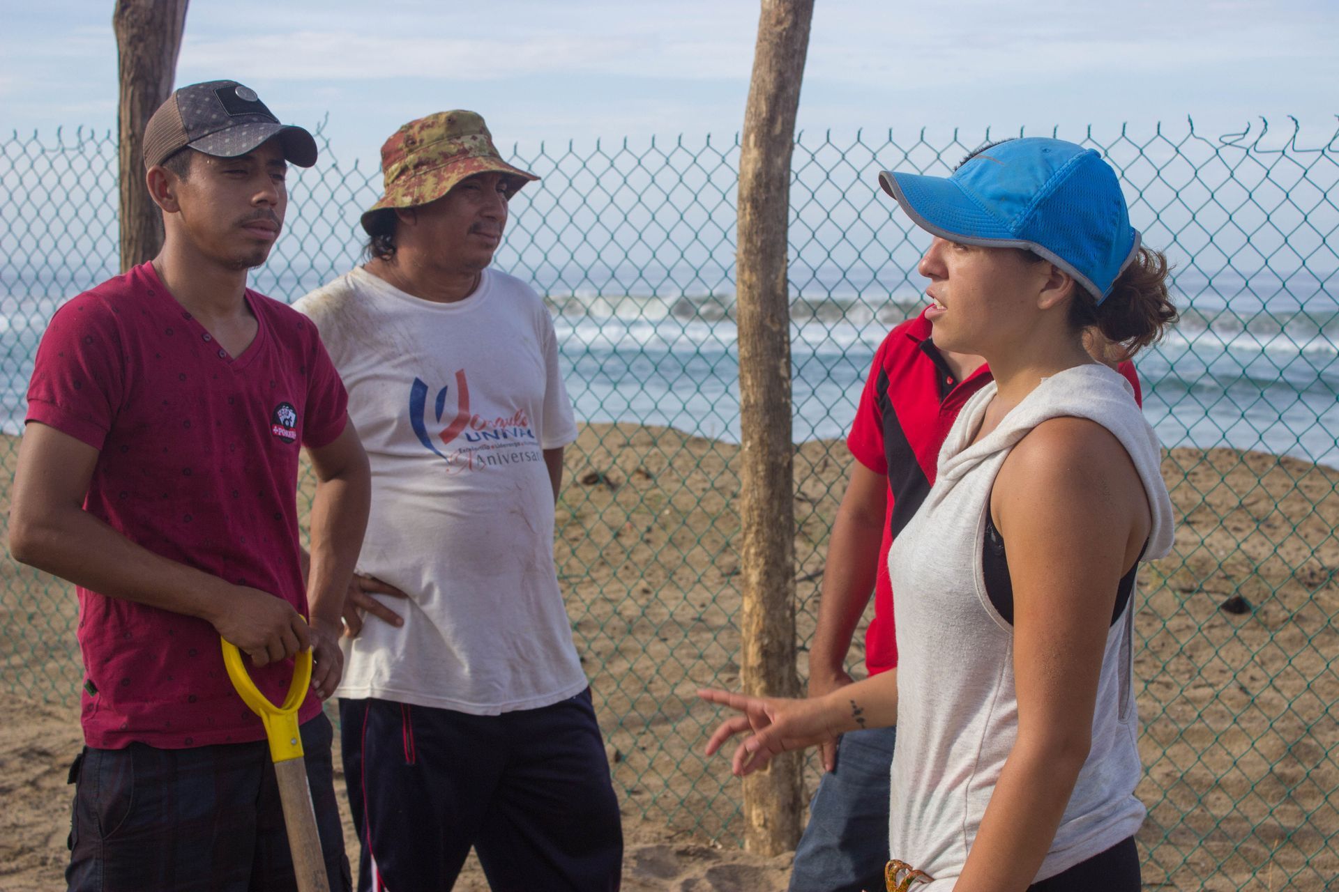 A group of people are standing on a beach talking to each other.