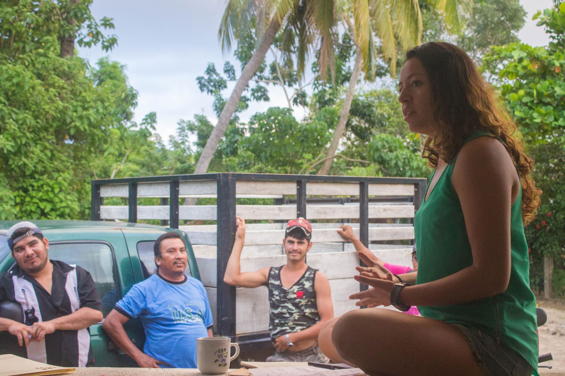 A woman is sitting on the ground talking to a group of people.