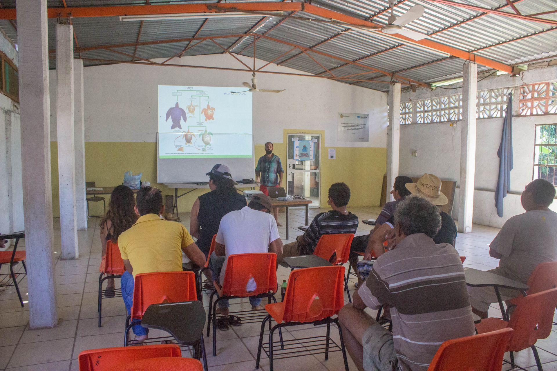 A group of people are sitting in chairs in front of a projector screen