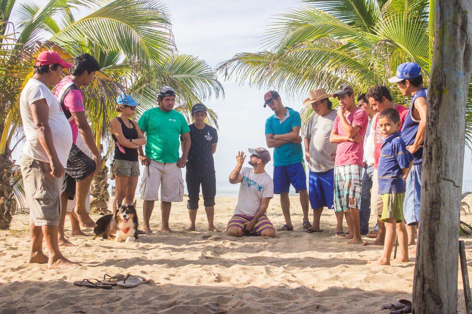 A group of people are standing around a man on the beach.