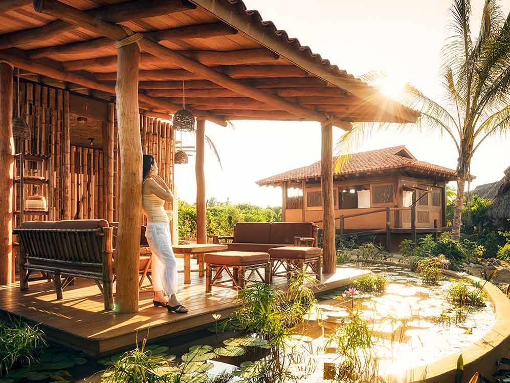 A woman is standing on a porch in front of a wooden house.