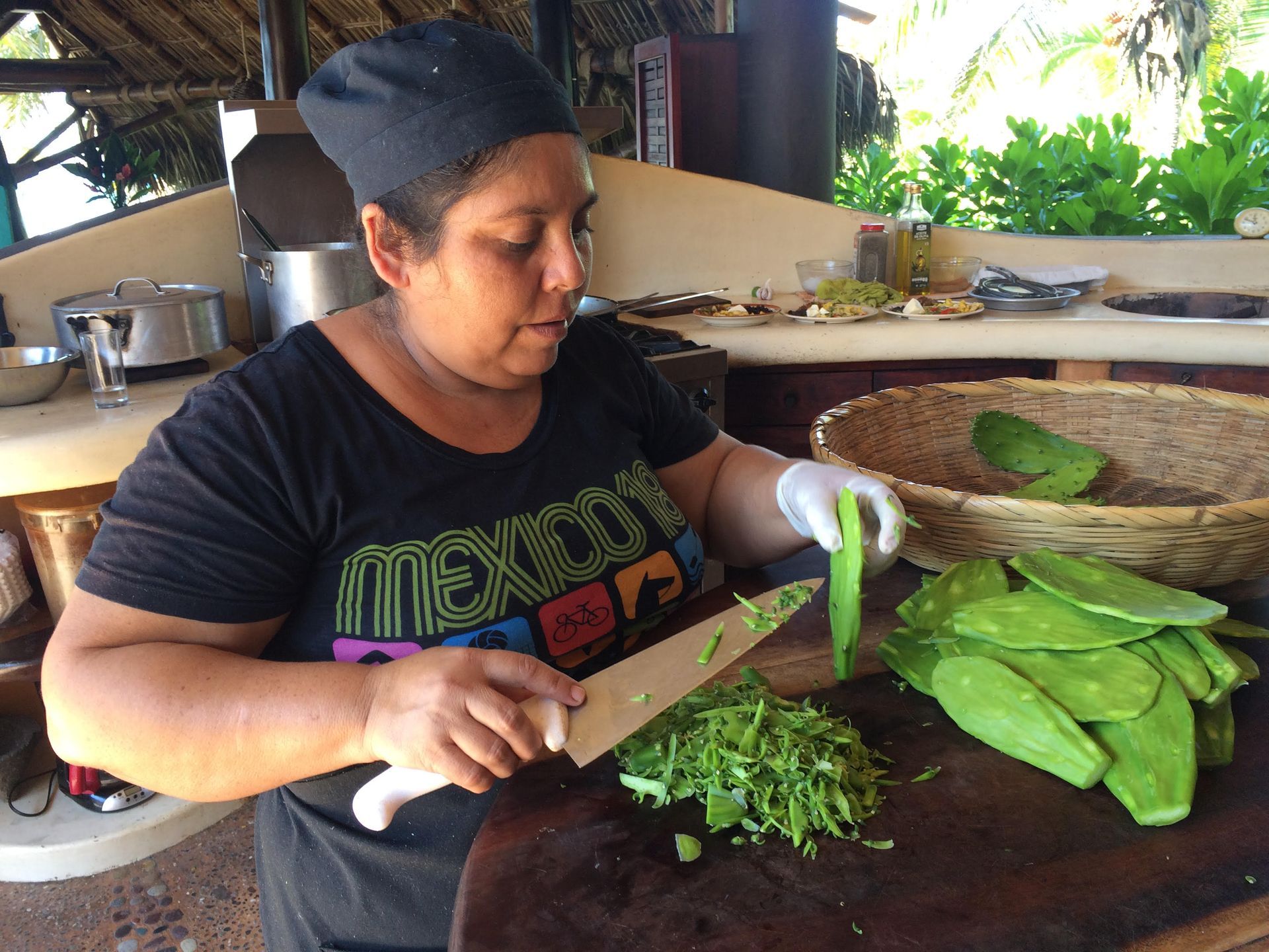 A woman wearing a mexican shirt is cutting vegetables