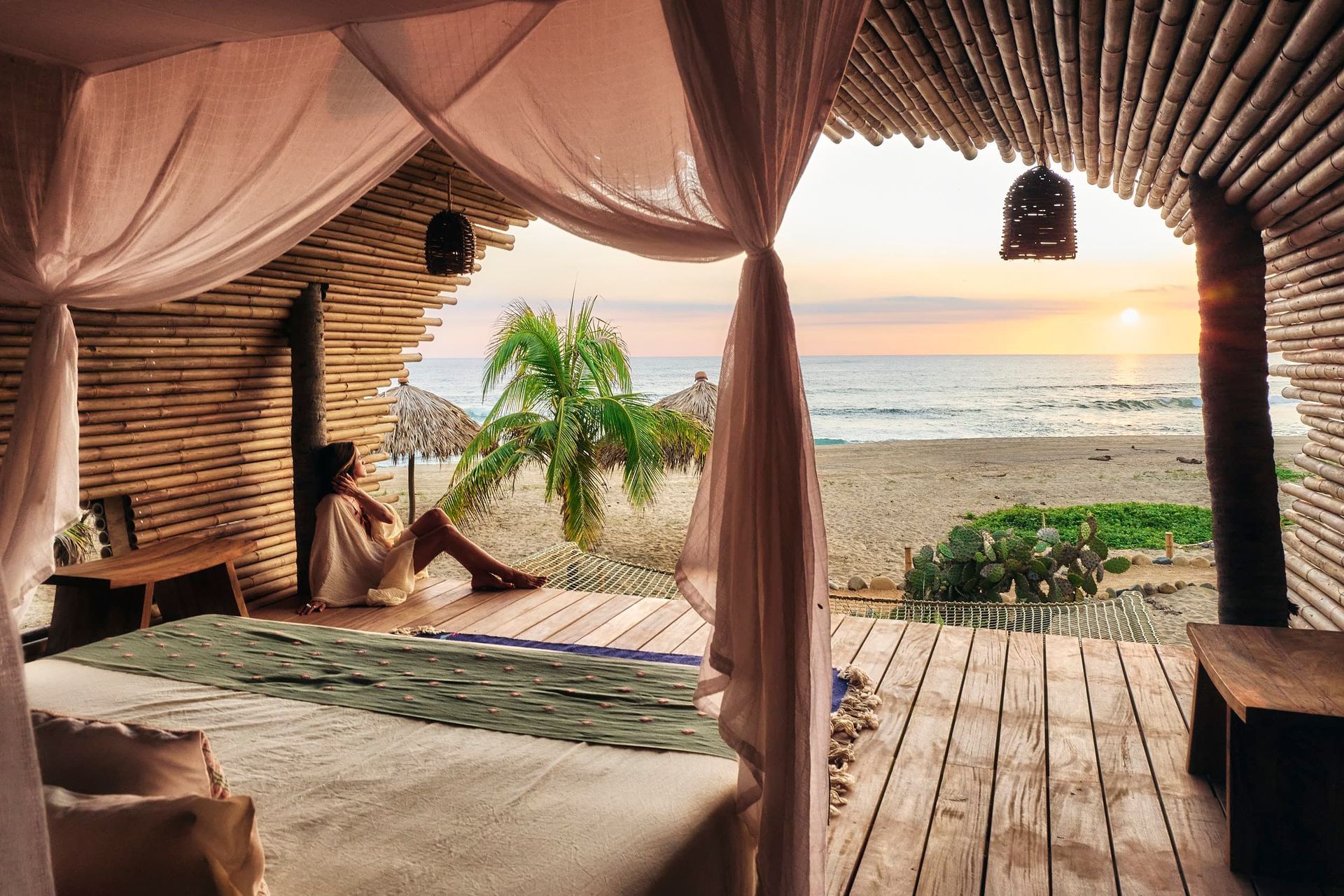 A woman is sitting on a bed in a room with a view of the ocean.
