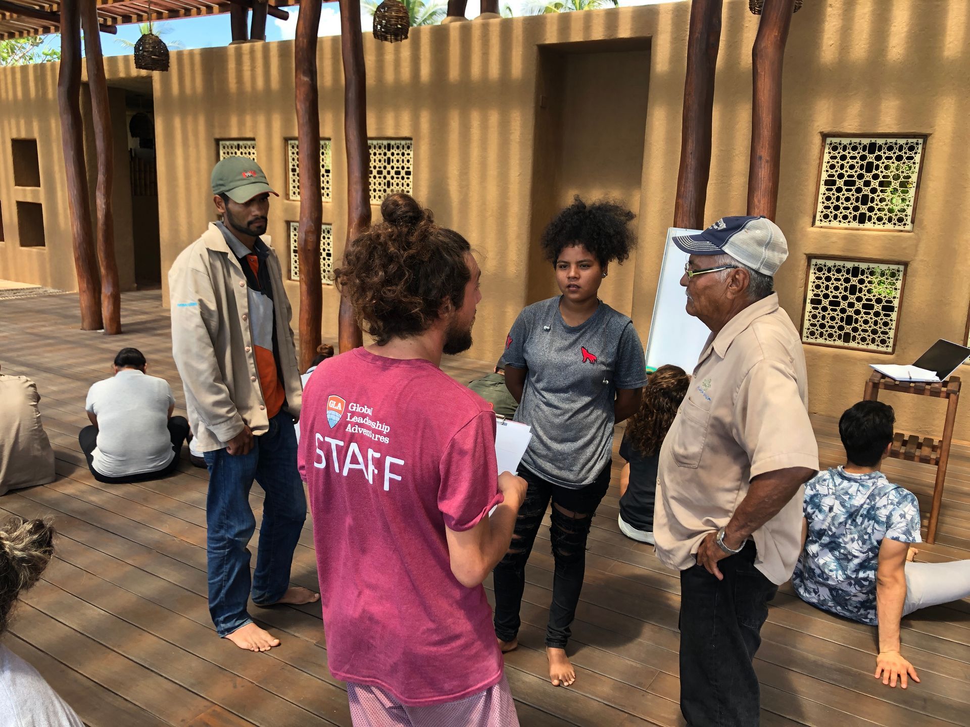 A woman in a pink staff shirt is talking to a group of people.