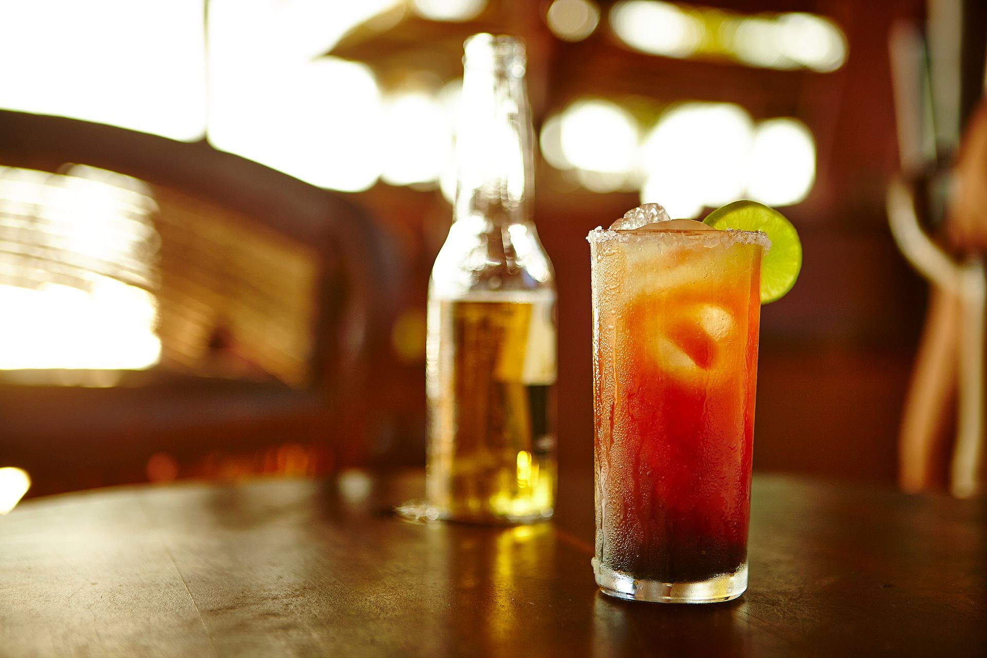 A bottle of beer and a glass of drink on a table.