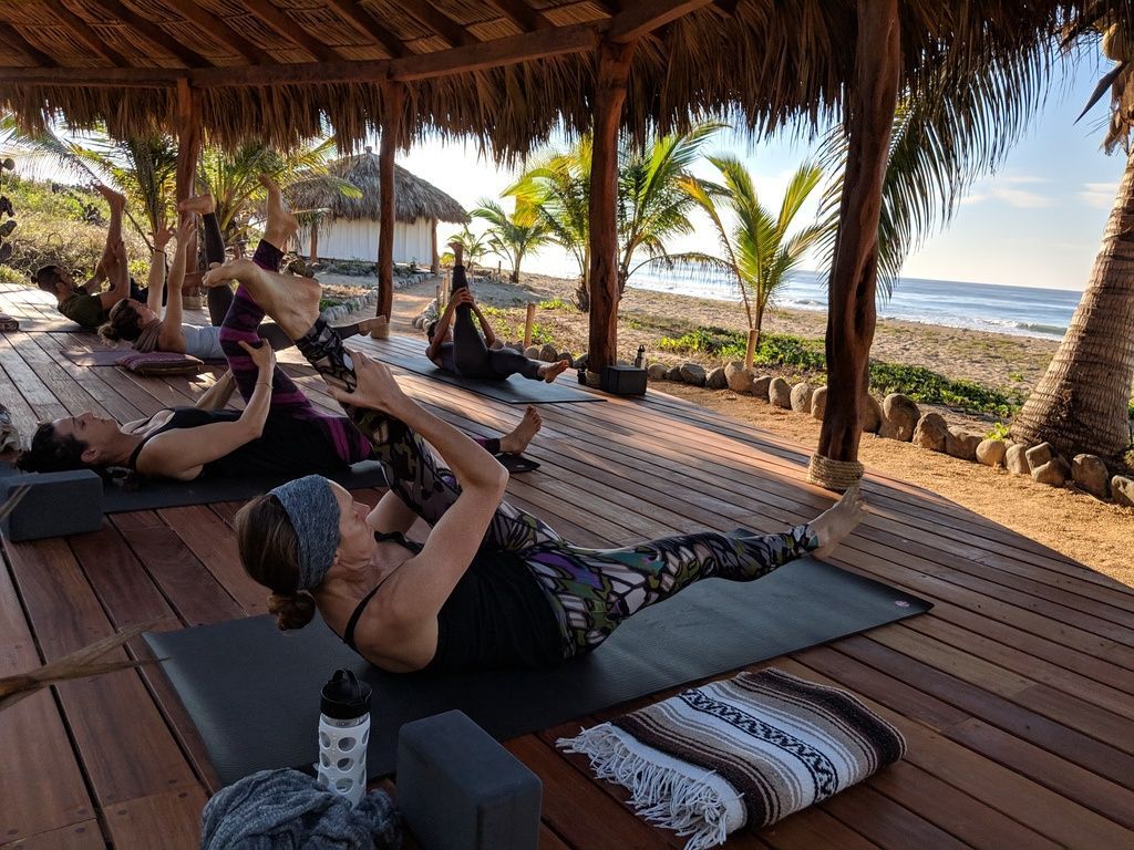 A group of people are doing yoga on a wooden deck.