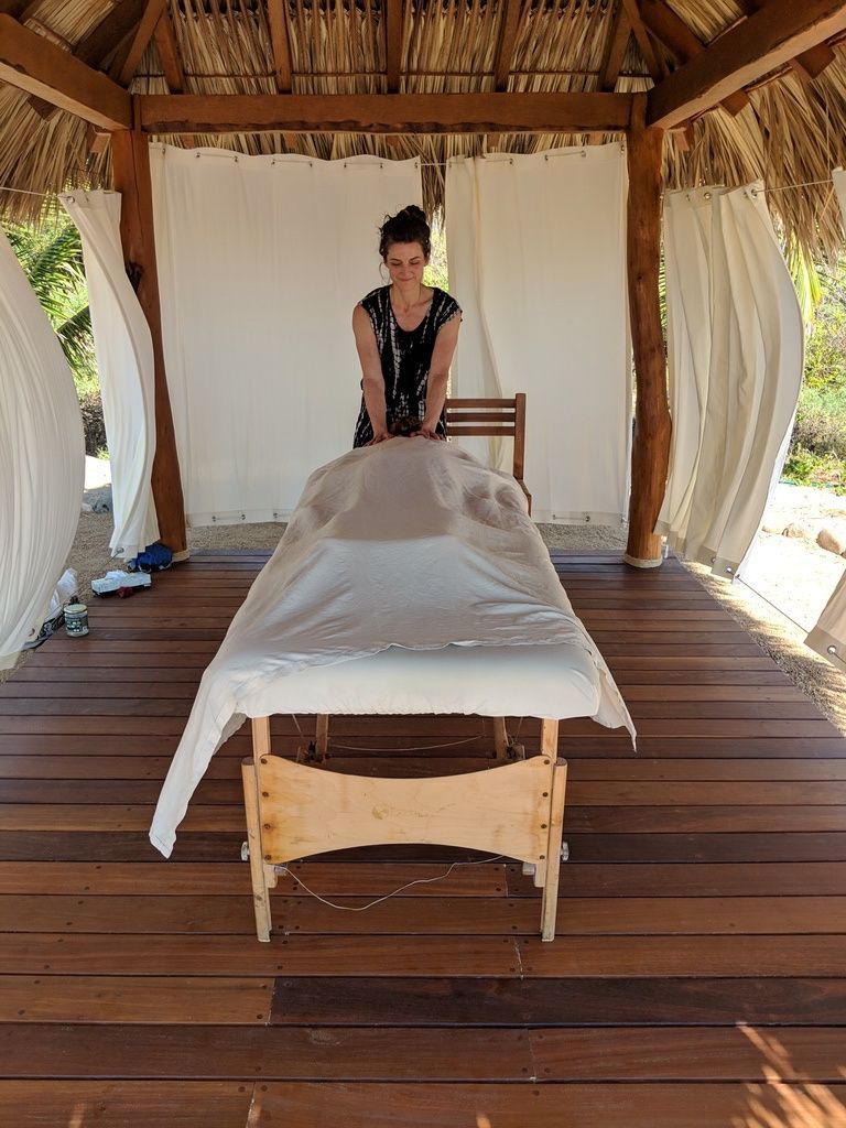 A woman is getting a massage on a wooden table under a gazebo.