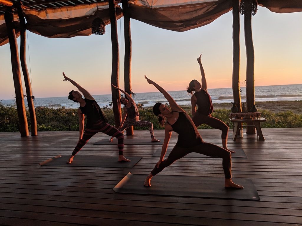 A group of people are doing yoga on a wooden deck.