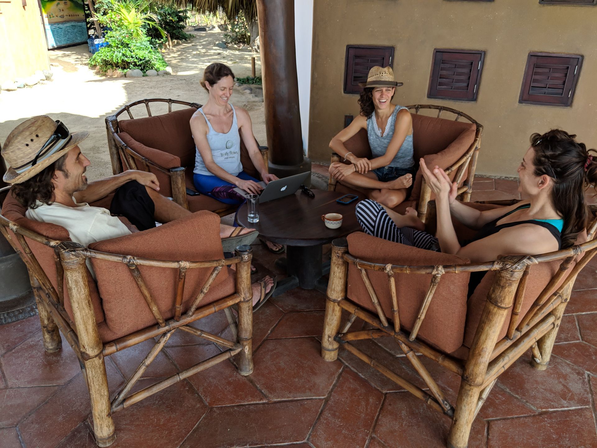 A group of people are sitting around a table with a laptop.