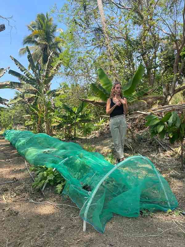 A woman is standing next to a green net in a field.