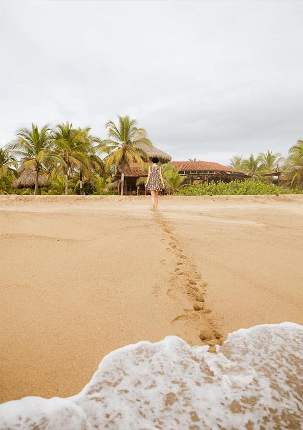 A woman is walking along a sandy beach.