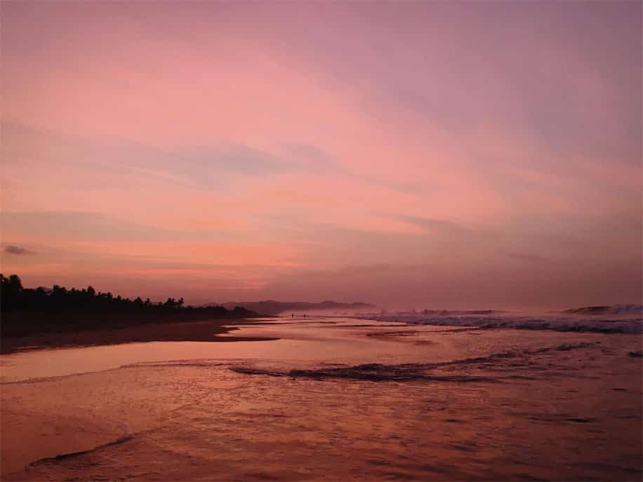 A sunset over a beach with a pink sky