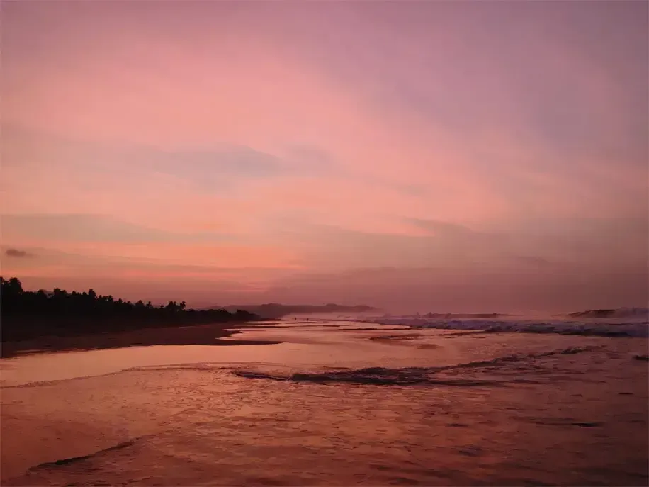 A sunset over a beach with a pink sky