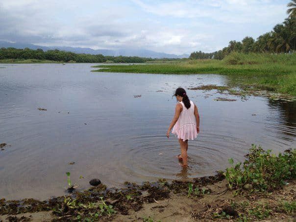 A woman in a pink dress is walking through a body of water.