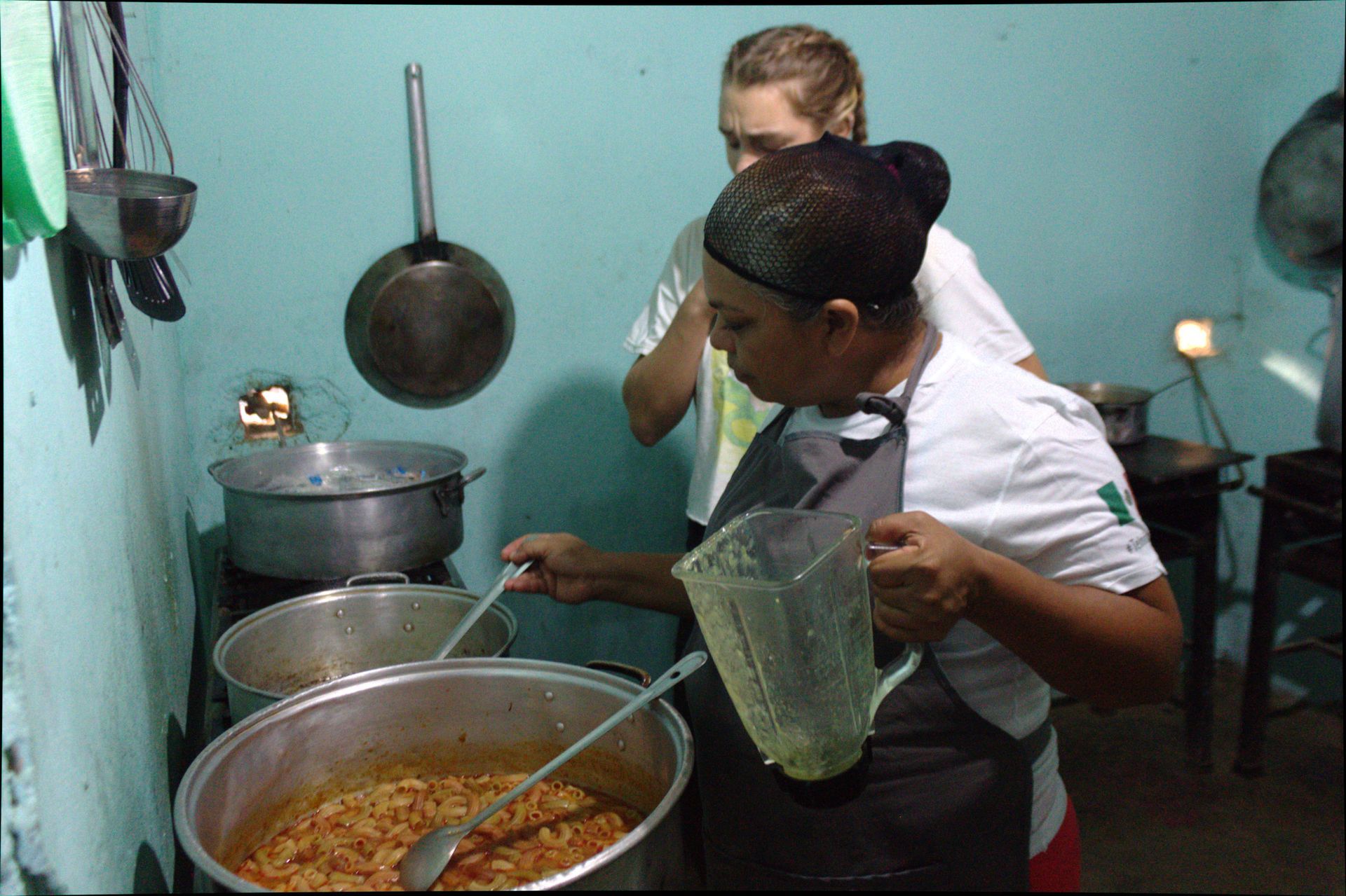 A woman is stirring a pot of food in a kitchen