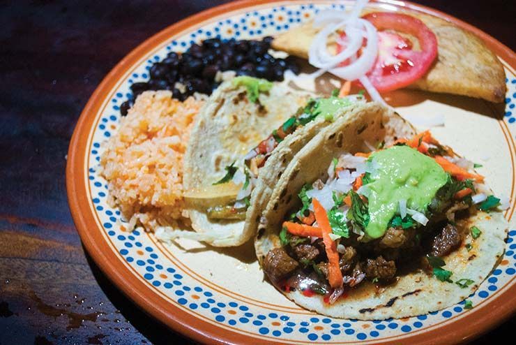 A plate of food with tacos rice and beans on a table