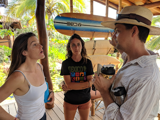 A man and two women are standing on a deck talking to each other.