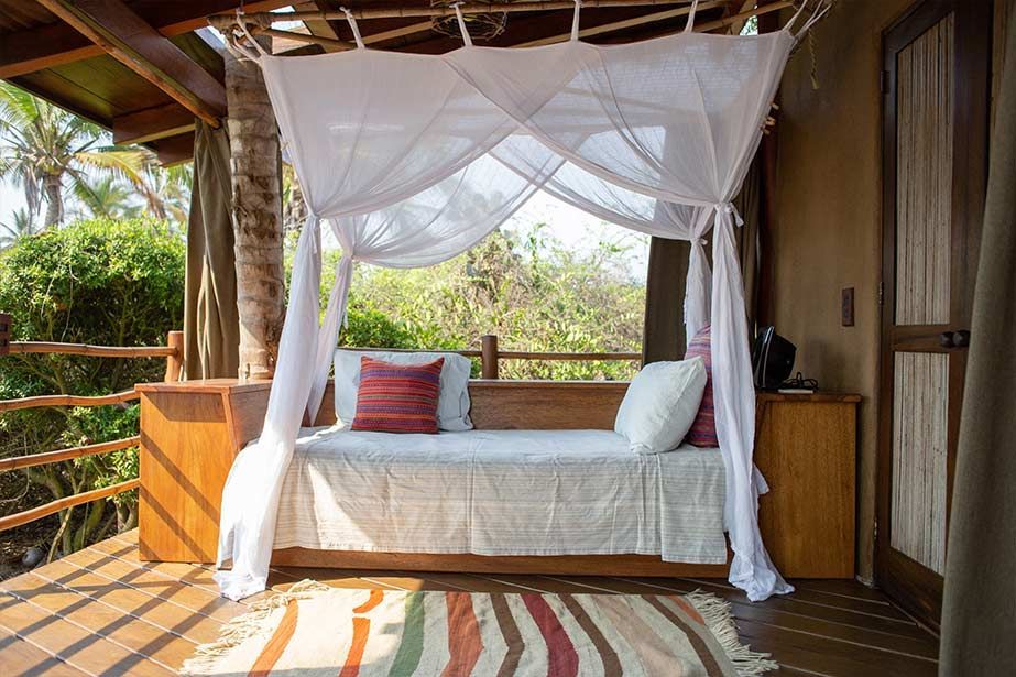 There is a canopy bed on the porch of a house.