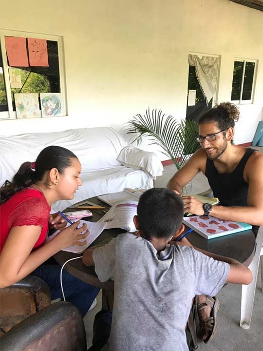 A man and two children are sitting at a table doing their homework.