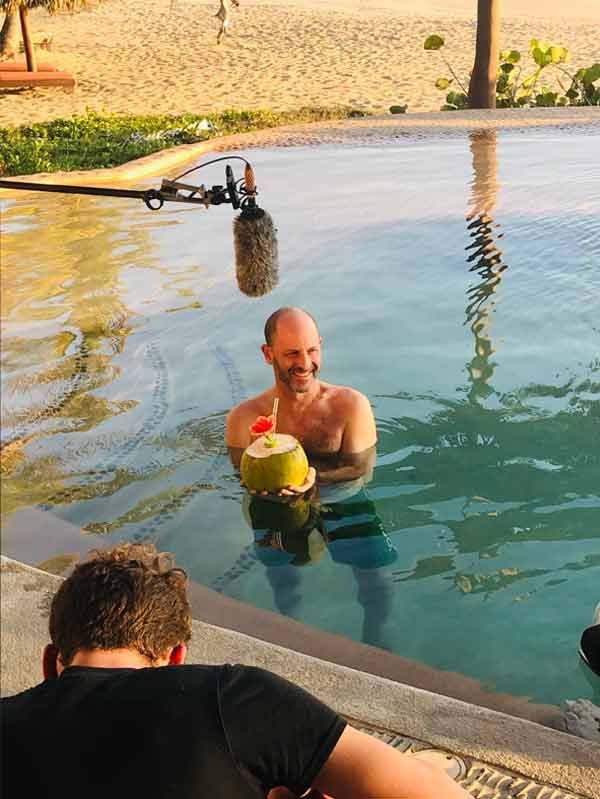 A man is holding a coconut in a swimming pool.