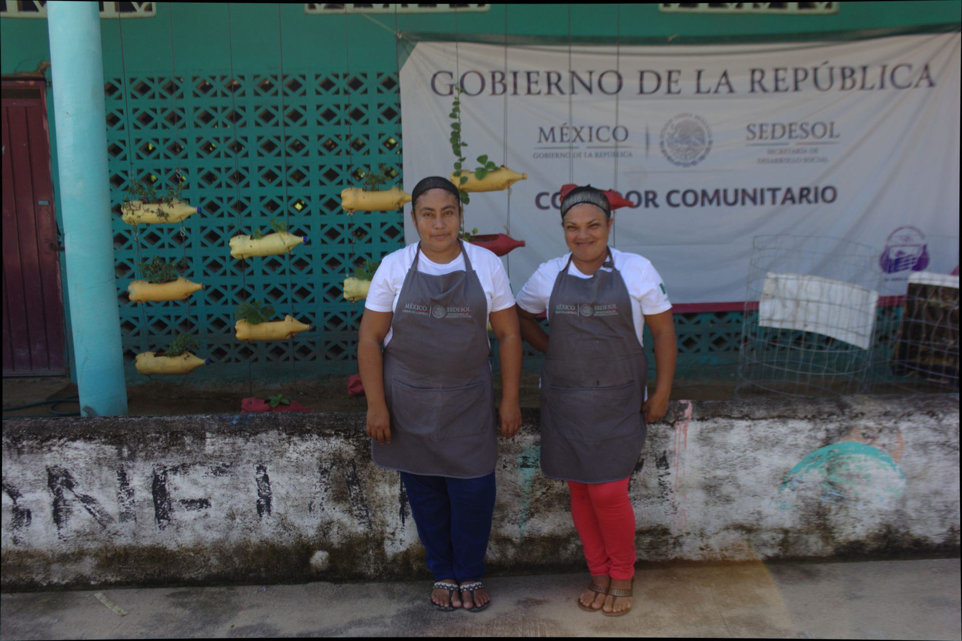 Two women standing in front of a sign that says gobierno de la republica