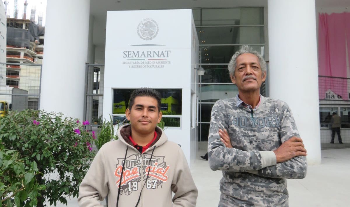 Two men are standing in front of a building that says semarnat