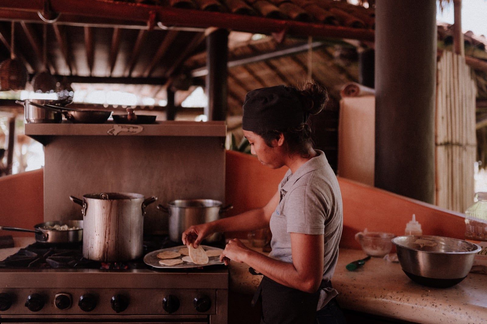A woman is preparing food on a stove in a kitchen.