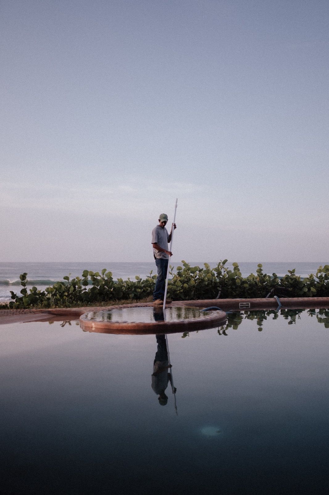 A man is standing on a raft in the middle of a swimming pool.