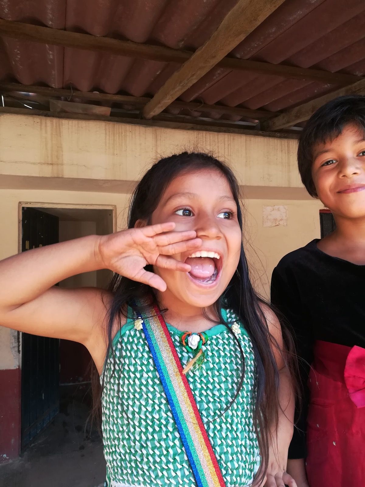 Two young girls are standing next to each other and one is making a funny face
