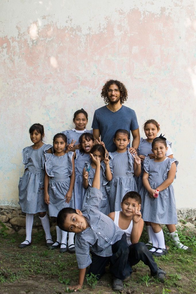 A group of children are posing for a picture in front of a wall.