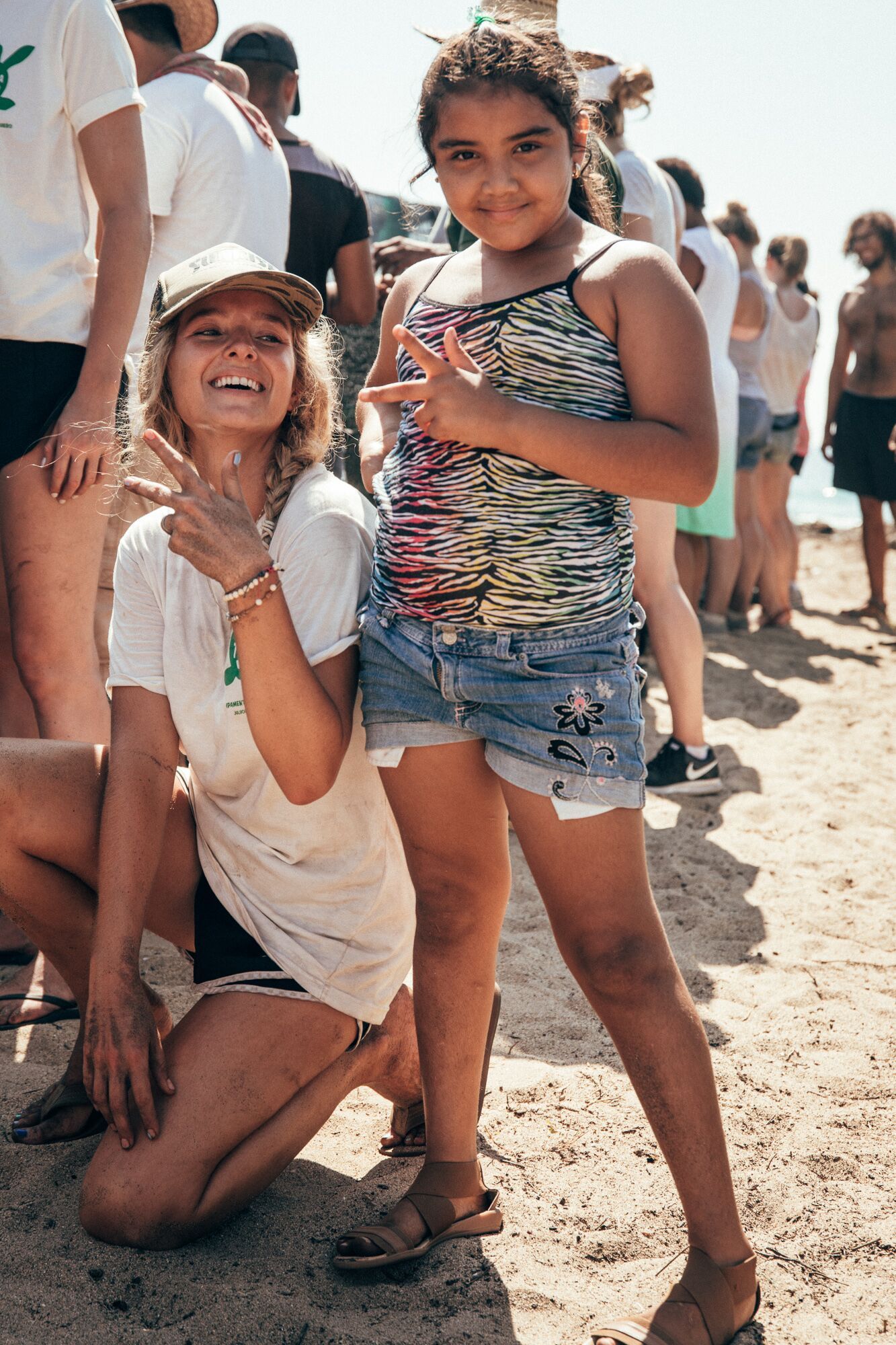 A woman and a little girl are posing for a picture on the beach.
