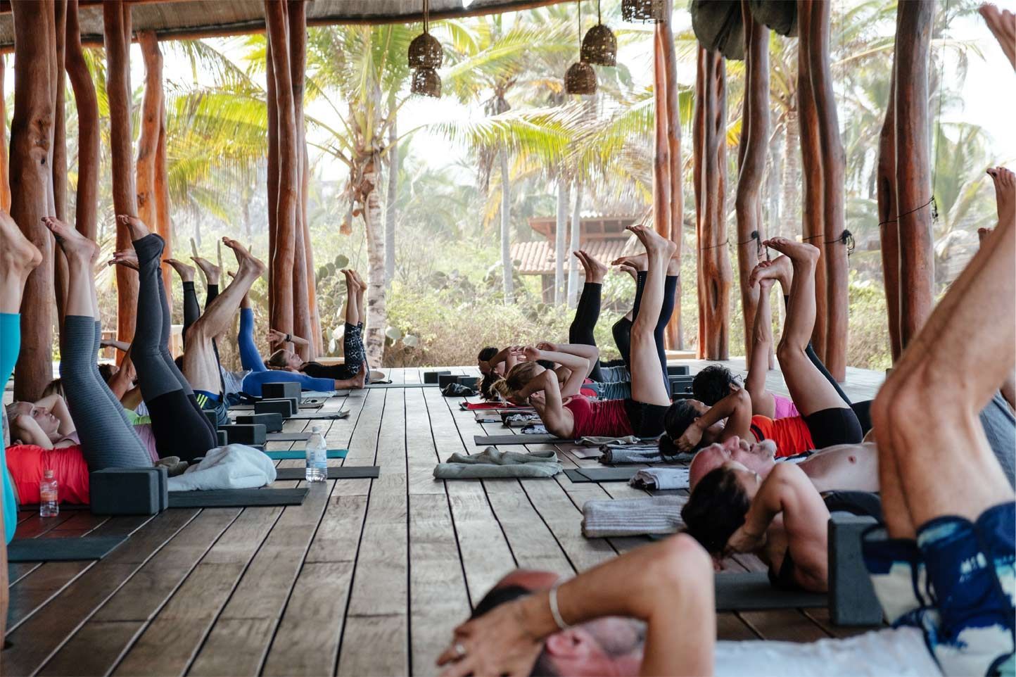 A group of people are doing yoga on a wooden deck.