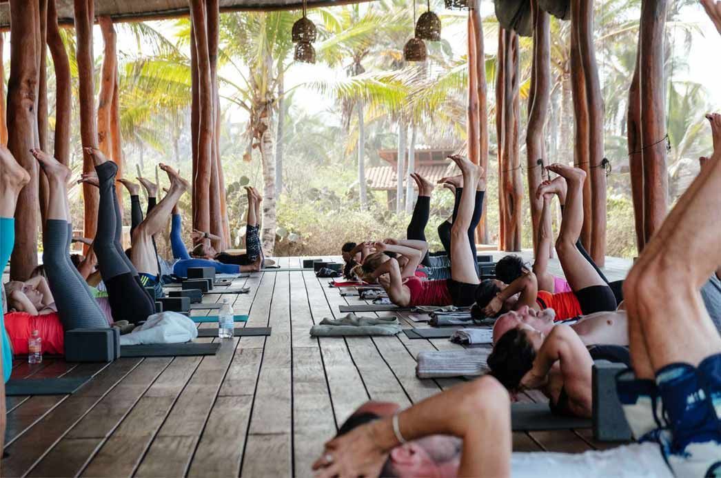 A group of people are doing yoga in a wooden building.