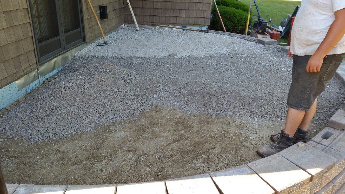 Worker on a gravel area in back of a house.